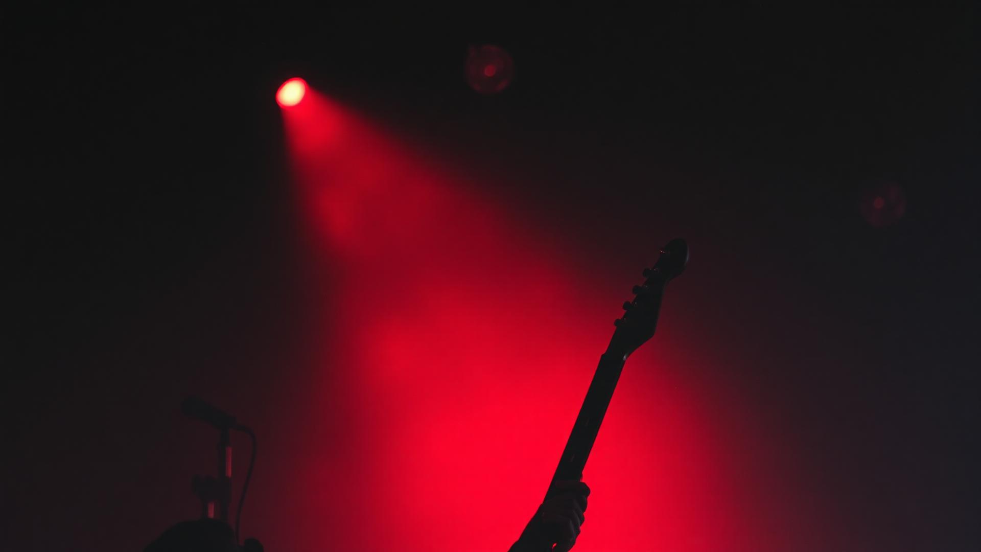 Red stage lights over a guitar silhouette